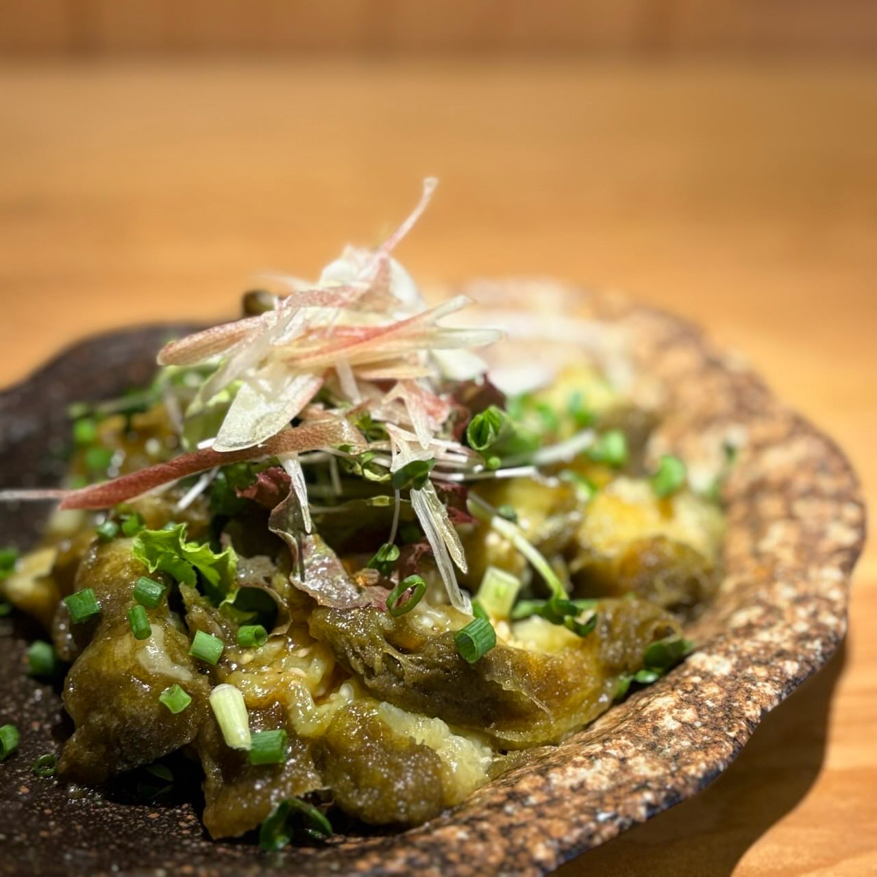 ステーキ茄子のカルパッチョ

水分をたっぷり蓄えた巨大なステーキ茄子を真っ黒に焦がし焼き茄子にして、とろろ昆布で締めカルパッチョにしちゃいました

トロける食感のステーキ茄子に焦げの香りと、とろろ昆布の旨味がプラスされ、もはやお魚より美味しいのでは？と思うほど茄子が美味しく食べれるカルパッチョです！

さっぱりとしたレモン醤油ドレッシングをかけているので、食欲がなくても箸が進む逸品です🤤

旬の食材なので期間限定ですが、是非召し上がってみてください！
ご来店お待ちしております