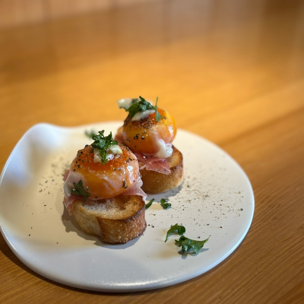 月見生ハムのブルスケッタ
イタリア語のローマ方言で「炭火であぶる」「焼く」を意味するbruscare(ブルスカーレ)から由来する、イタリア発祥の前菜ブルスケッタ🥖
@four_en_pierre
すいととではフール・アン・ピエールさんで焼いて頂いたバケットを使用して作っています!
パン屋さんのバケットはやっぱり美味しいんです🤤
そのバケットに負けないよう、じっくり丁寧に火入れをした卵黄のコンフィと生ハムを乗せ仕上げました🥚
卵黄の旨味と生ハムの塩味、バケットのかおりが最高です❣️
期間限定です、この機会に是非お召し上がりください!
本日もご来店お待ちしております